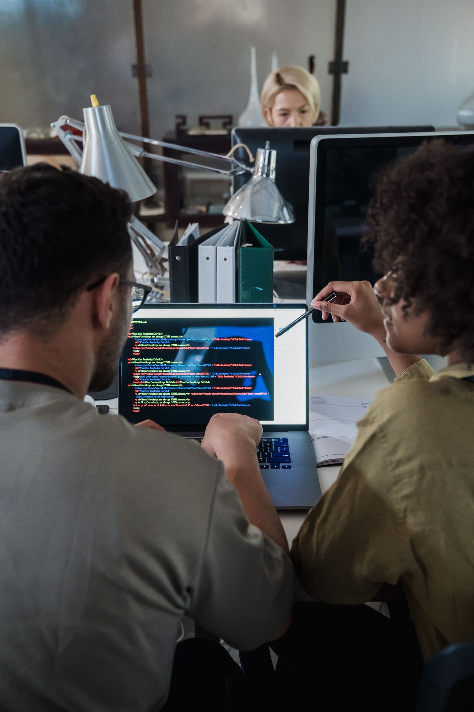 Equipe discutindo desenvolvimento de software em frente a um laptop com código